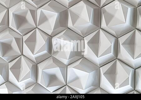 3D decorative wall for the interior of an unusual hexagonal geometric shape similar to honeycombs. White light background with a pattern imitating a t Stock Photo