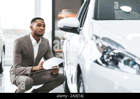 Insurance Agent Checking Car Taking Notes In Dealership Store Stock Photo