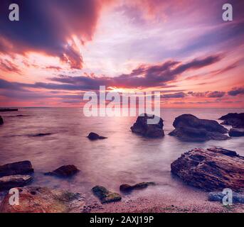 Beautiful colorful sunrise at the sea with dramatic clouds and boulders. Beauty world natural outdoors travel background Stock Photo