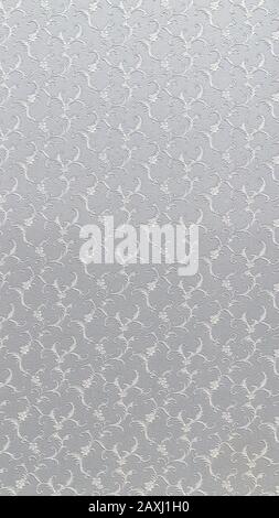 Embossed floral pattern on light gray paper. Textured paper with copy space. Motley gray-brown paper surface, texture closeup. Stock Photo