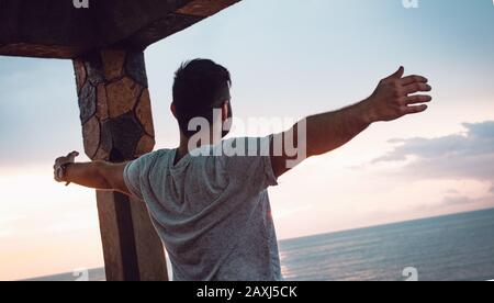 Man who opens his arms to the sea view and finds peace. Freedom Concept. Stock Photo