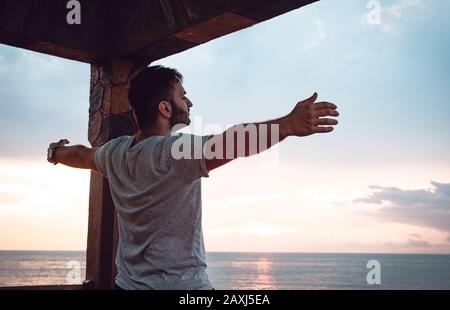 Man who opens his arms to the sea view and finds peace. Freedom Concept. Stock Photo