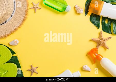 Beach accessories with straw hat, sunscreen bottle and seastar on yelow background top view with copy space. Stock Photo