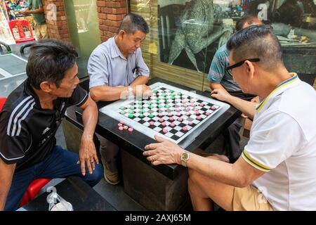 Local Chinese men playing the local and popular Singapore checkers in a back street of Chinatown, Singapore, Asia Stock Photo