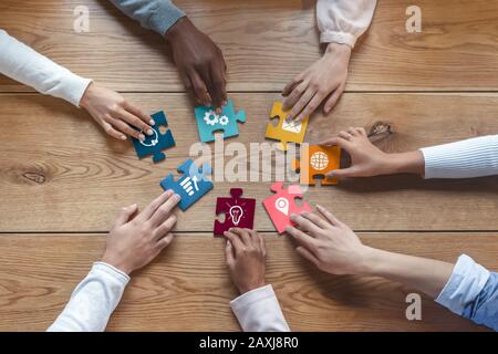 Hands of international coworkers putting colorful puzzles together Stock Photo