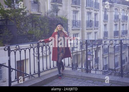 Blonde lady in a red coat and black beret in Paris, by pasakdek Stock Photo