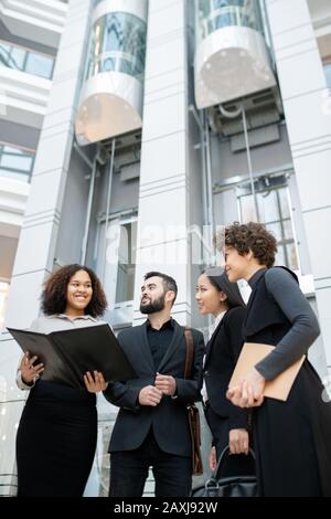 Smiling Afro-American manager holding open folder while presenting project plan to colleagues in office Stock Photo