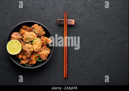 Chicken Karaage in black bowl at dark slate background. Karaage is traditional japanese cuisine dish with deep fried marinated chicken. Copy space. To Stock Photo