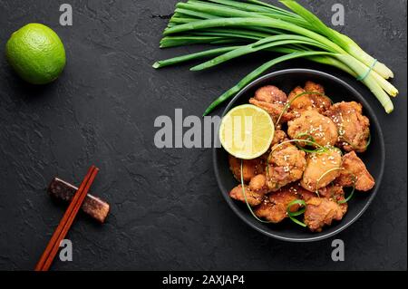 Chicken Karaage in black bowl at dark slate background. Karaage is traditional japanese cuisine dish with deep fried marinated chicken. Copy space. To Stock Photo