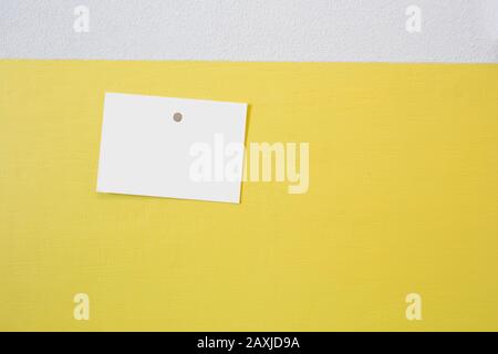 Blank postcard frame hanging on a yellow wall with a pushpin, concrete background texture, space for text Stock Photo