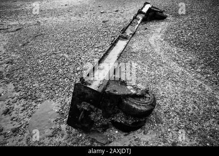 Cold War era wheeled weapons trolly sunken on the beach due to coastal erosion. Stock Photo