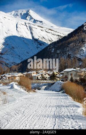 Small Town at the foot of the high mountains in the winter sunny day with track for winter sports. Road for snowmobiles, dog sledding and skiing.. Fra Stock Photo