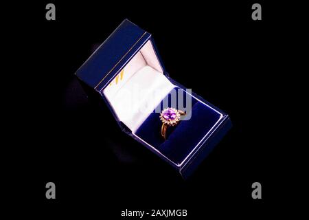 A ladies gold ring with Ruby and Diamonds on a black background in a blue box.. Stock Photo