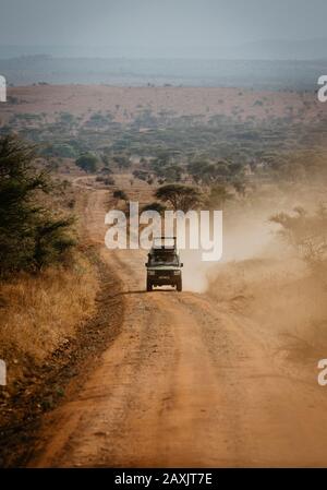 A safari car on a long dusty road alone through the Serengeti, Serengeti National Park, Tanzania Stock Photo