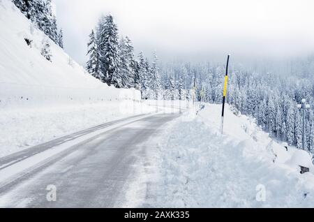 Empty snow covered mountain road on a foggy winter day Stock Photo