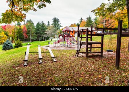 Playground in a park surrounded by colourul autumnal trees on a cloudy morning. Fall foliage. Stock Photo