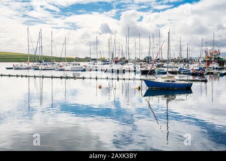 Yachts moored in a harbour on a partly cloudy summer day