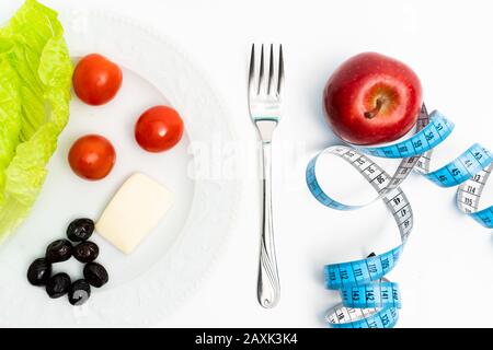 isolated red apple and plate of healthy meals next to tape measuring on white background. Diet and healthy living concept Stock Photo