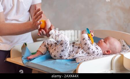 Dad is caring for the baby. A father gives his child a ball foot massage. Stock Photo