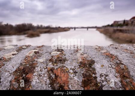 Tagus River in Talavera de la Reina, taken from old roman bridge in a closeup of old bridge wall with detail of lichens and mosses. Stock Photo