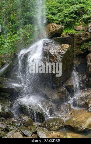 Small waterfall hitting and splash on the surface of hard rocks, near Taipei, Taiwan - On a sunny day during summer time Stock Photo