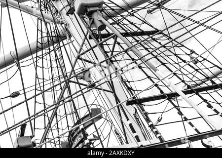 Monochrome image of mast with rigging and rolled up sails of old polish sailing ship Dar Pomorza Stock Photo