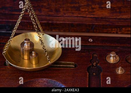 Close-up of an old gold scale with various decorations in a wooden box for storage. Stock Photo