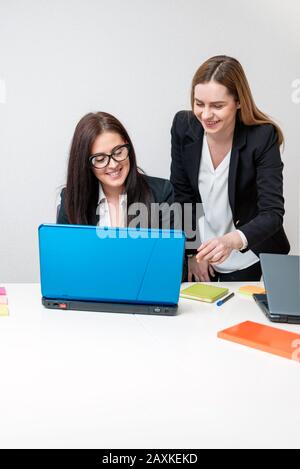 Two Happy coworkers smiling and working on laptop in office Stock Photo