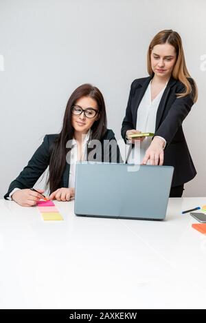 Two Happy coworkers smiling and working on laptop in office Stock Photo