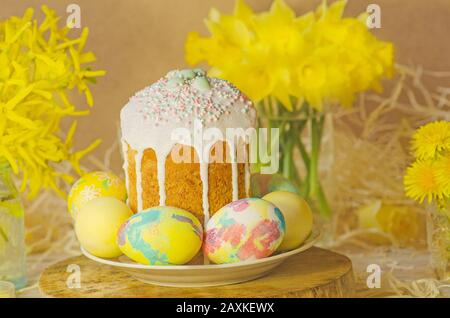 Cake with sprinkles and easter eggs. Easter cake by festive attributes. Easter composition with cake, coloured eggs and flowers Stock Photo
