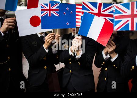 Close up of people in uniform waving small national flags.