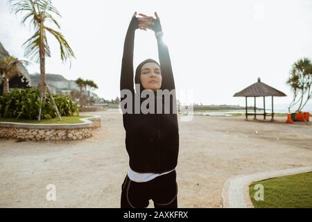 Young fitness muslim woman runner stretching legs before run Stock Photo