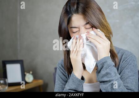 Asian woman sick of the flu and sneezing In paper wipe. Stock Photo