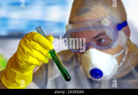 A scientist in a protective suit watching and analyzing the process in a test tube. Concept of innovation, research, science, virus, biology, chemistr Stock Photo
