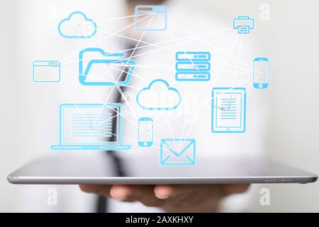 Businessman pressing a virtual projection of different icons connected with cloud Stock Photo