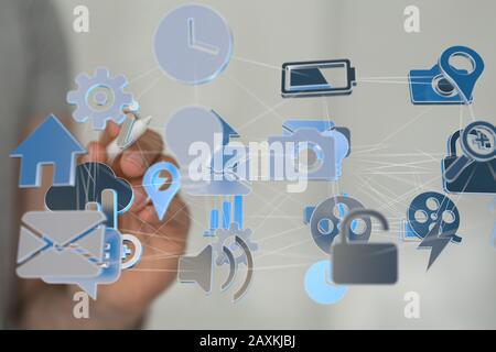 Businessman pressing a virtual projection of different icons connected with cloud Stock Photo