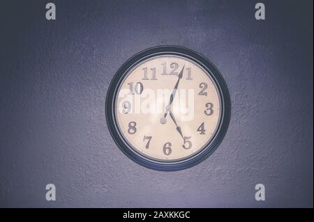 Watch hanging on the wall displaying five o'clock Stock Photo