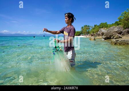 Fisherman fishing with fishnet bait fishes in the lagoon, White beach, Moalboal, Cebu, Philippines Stock Photo