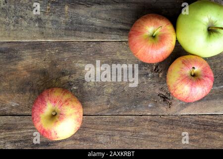 Top view of three red apples and one green apple on a old wood table Stock Photo