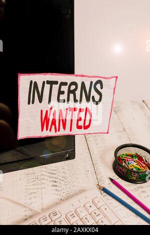 Handwriting text writing Interns Wanted. Conceptual photo temporary position with an emphasis on the job training Note paper taped to black computer s Stock Photo