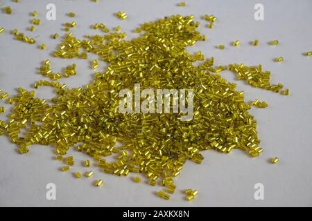 Yellow tubular toho beads on light cream background. Beads used for embelishing garments. Stock Photo