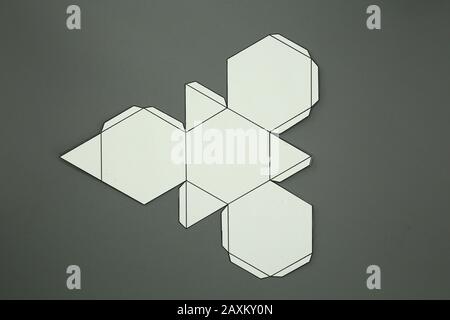 Geometric shape cut out of paper and photographed from above on grey background. Geometry net of Archimedean solid Truncated tetrahedron. 2-dimensiona Stock Photo