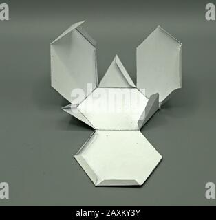 Geometric shape cut out of paper and photographed on grey background. Geometry net of Archimedean solid Truncated tetrahedron. 2-dimensional shape tha Stock Photo