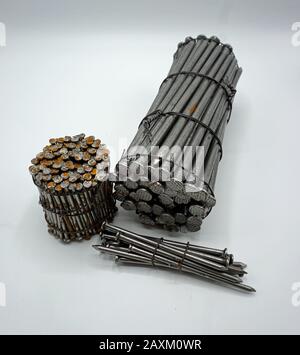 Steel construction nails of different lengths tied together in groups. Common nails and spikes on white background. New and rusty nails and spikes det Stock Photo