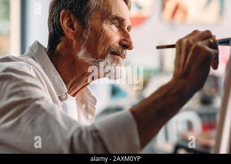 Close up portrait of senior painter drawing on canvas in studio Stock Photo