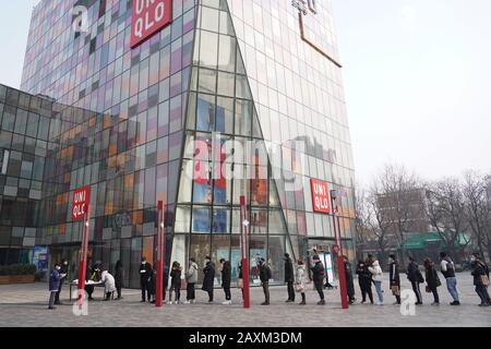 Beijing, China. 12th Feb, 2020. People line up to take body temperature checks at Sanlitun business area in Beijing, capital of China, on Feb. 12, 2020. Work and production has resumed gradually in enterprises, communities and malls, etc. in Beijing since Feb. 10 with comprehensive measures taken to prevent and control the epidemic caused by the novel coronavirus. Credit: Ju Huanzong/Xinhua/Alamy Live News Stock Photo