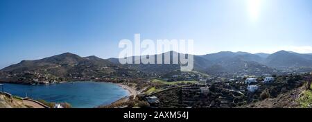 Tzia, Kea island, Greece. Aerial and panoramic view of Otzias bay. Houses next to the clear and calm blue sea under sunbeams. Panorama, banner. Stock Photo