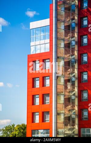 modern building with a red square windows and mirrored glass on the background of blue sky with clouds on a sunny day Stock Photo