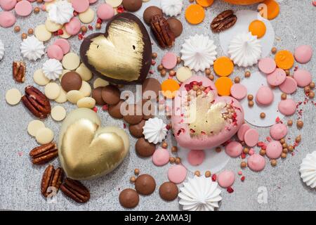 Assorted pink, orange, brown and green chocolate hearts with meringues, pecan nuts and chocolate drops Stock Photo