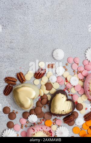 Assorted pink, orange, brown and green chocolate hearts with meringues, pecan nuts and chocolate drops Stock Photo